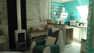 a kitchen with a fireplace and a chair in a room at Gîte Shabby Blue in Saint-Cernin
