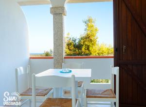 a white table and chairs in a room with a window at Villa Malamuri in Budoni