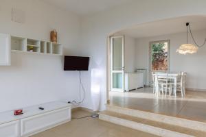 a white living room with a tv and a table at Villa Martina in Pietrasanta