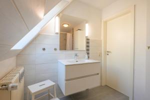 a white bathroom with a sink and a staircase at Ferienhof Harrsen in Pellworm +79 photos