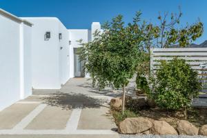 a white building with a tree and a white fence at A The Country House in Tinos
