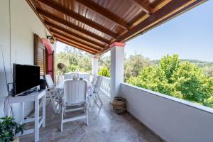 a balcony with a table and chairs and a television at Nana's House Holidays Greece in Dragotiná