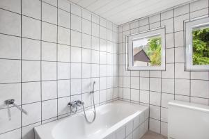a white bathroom with a tub and a window at Ferienwohnung Triska in Balve +15 photos