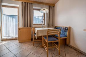 a dining room with a table and chairs and windows at App Sonne Nr 21 in Lutago
