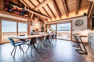a dining room with a table and chairs and windows at Le Perray Alpine Lodge in Abondance