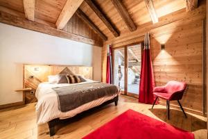 a bedroom with a bed and a red chair at Le Perray Alpine Lodge in Abondance