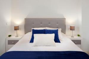 a bed with blue and white pillows and two lamps at Playamarinsa in Torre del Mar