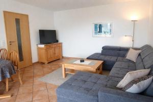 a living room with a couch and a tv at Haus Sonnenseite Wohnung Säntis in Wasserburg