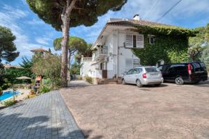 a white house with two cars parked in a driveway at Casa Isabel in Calonge