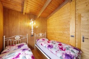 a bedroom with two beds in a wooden room at Orserose Chalet 3 I Ciodi in Forno di Zoldo +3 photos