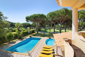 a swimming pool with yellow chairs next to a house at V4 Galeão Vilamoura in Vilamoura