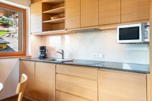 a kitchen with a sink and a microwave at Villa Solinda App Puccini in Selva di Val Gardena +26 photos