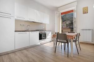 a kitchen with white cabinets and a table with chairs at Moneglia Mare in Moneglia