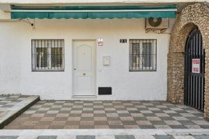 a white building with a door and a checkered floor at Verano Azul in Nerja +16 photos