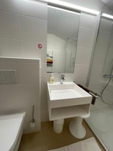 a white bathroom with a sink and a mirror at Fewo 2 am Auweg in Hirschegg