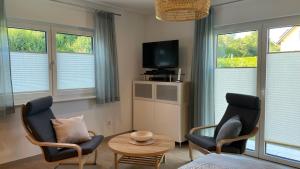 a living room with two chairs and a table and a tv at Ferienwohnung Am Wall in Radeberg