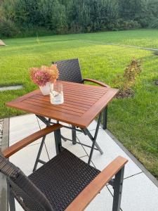 a wooden table and chair with a vase of flowers at Ferienwohnung Am Wall in Radeberg