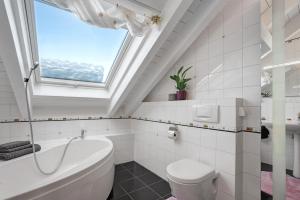 a bathroom with a white tub and a window at Dachgeschosswohnung in Hofolding in Brunnthal +18 photos