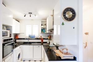 a white kitchen with a clock on the wall at Appartement Urrugne in Urrugne +12 photos