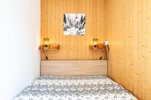 a bedroom with a bed and two lights on the wall at victorsun2 in La Clusaz