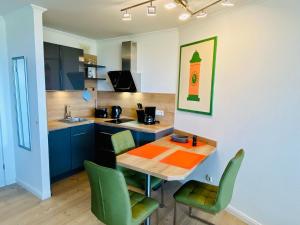 a kitchen with a wooden table and green chairs at 307 im Lord Nelson in Cuxhaven