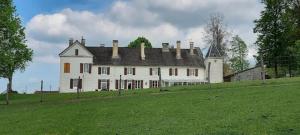 a large white house on a hill with a green field at Domaine du Val Bruant in Arc-en-Barrois