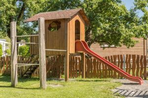 a wooden playground with a slide and a house at Ferienhaus Am Sedelbach in Deggenhausertal