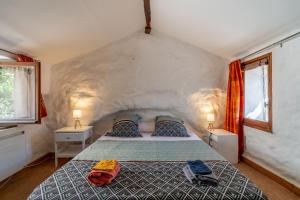 a bedroom with a large bed with two windows at Maison dans Village médiéval in Olargues