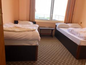 two twin beds in a room with a window at Manakamana hotel in Pāti Bhanjyāng