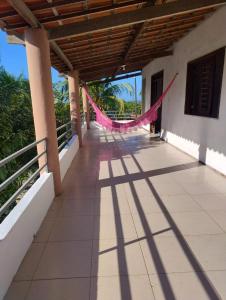 a porch of a house with a pink hammock on it at Casa da Mari in Caucaia