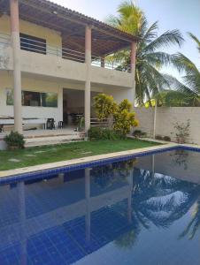 a villa with a swimming pool in front of a house at Casa da Mari in Caucaia