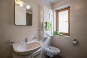 a bathroom with a sink and a toilet and a mirror at Golserhof Sonne in Cadipietra