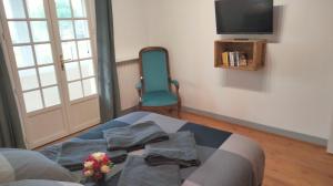 a room with a bed and a chair and a television at Au Nid Douillet in Bourges