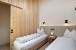 two beds in a room with wooden walls at Oberplunerhof Luxury Chalet Woods in Chienes