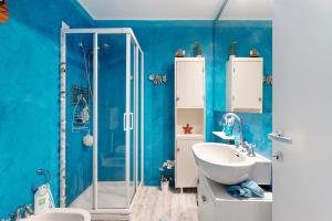 a blue bathroom with a sink and a shower at Attico con terrazza a Viareggio in Viareggio +15 photos