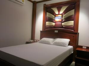 a bedroom with a bed with a wooden headboard at SP Park Cha-am in Cha Am