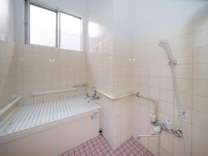 a white tiled bathroom with a tub and a window at 小豆島宿いたち in Tonosho +33 photos
