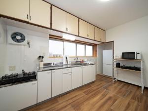 a large kitchen with white cabinets and a wooden floor at 小豆島宿いたち in Tonosho