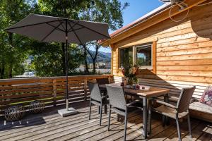 a wooden deck with a table with chairs and an umbrella at Alpenchalet zum Hirsch in Aschau