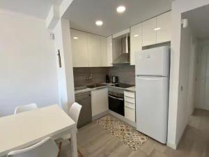 a white kitchen with a table and a white refrigerator at Montiro in L'Escala