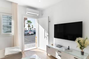 a white living room with a flat screen tv on a wall at Apartamento Calderon in Barbate