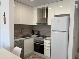 a kitchen with white cabinets and a white refrigerator at Montiro in L'Escala