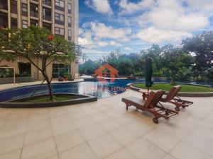 a couple of chairs sitting next to a pool at Cozy 2BR Bintaro Park View Pool in Jakarta