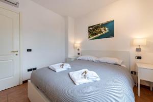 a white bedroom with two towels on a bed at Villa Bornico Margherita in Toscolano Maderno +15 photos