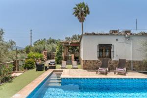 a swimming pool with chairs next to a house at Las Gallinas Cottage Orgiva in Órgiva