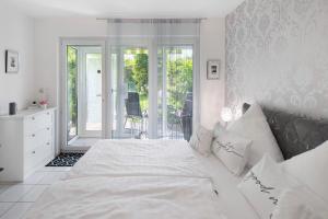 a white bedroom with a bed and a balcony at Ferienwohnung an der Dönche in Kassel