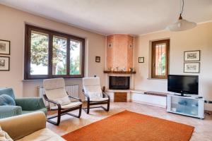a living room with a tv and a couch and chairs at Villa Del Riccio in Magione