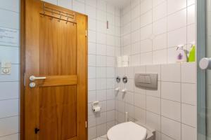 a bathroom with a toilet and a wooden door at Ferienwohnung Chiemgau - erleben in Siegsdorf +16 photos
