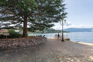 a group of people sitting on a brick sidewalk next to the water at Casa Làrisa Lago Maggiore in Laveno-Mombello