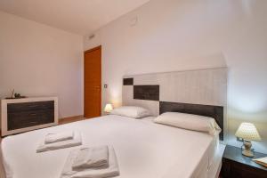 a white bedroom with a large white bed with two towels at Villa Olivetta con piscina in Alghero +37 photos